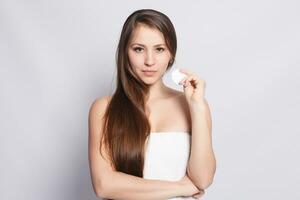 Happy smiling beautiful young woman cleaning skin by cotton pad. photo