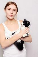 Beautiful smiling woman with a kitten in her arms, studio picture, close-up photo