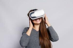 Woman with virtual reality goggles. Studio shot, gray background photo