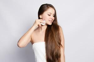 Happy smiling beautiful young woman cleaning skin by cotton pad. photo