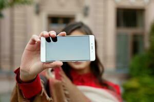 portrait of young attractive female in stylish outfit making selfie photo