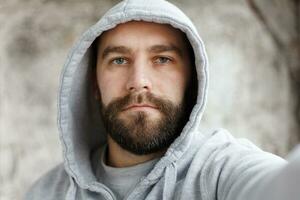 bearded man on a gray background makes a selfi photo