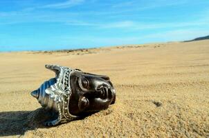 un negro y plata Buda cabeza tendido en el arena foto
