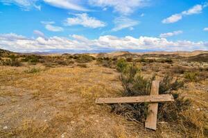 un antiguo de madera cruzar se sienta en el medio de un seco campo foto