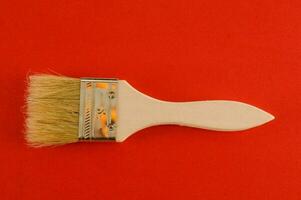 a brush with a wooden handle on a red background photo