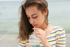 Beach woman drinking cold drink beverage having fun at beach party. photo