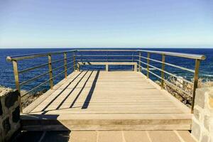 a wooden bridge over the ocean with a railing photo