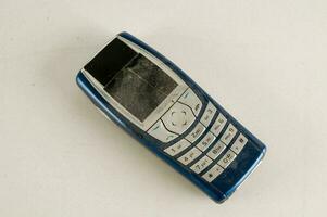 a blue and white cell phone laying on a white surface photo