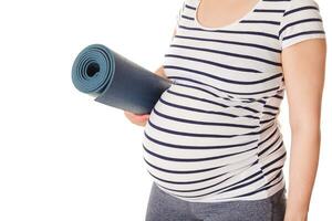 embarazada mujer en pie con yoga estera foto