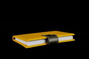 a yellow leather notebook with a black leather strap photo