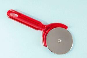 a red plastic pizza cutter on a blue surface photo