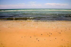 a sandy beach with waves and water photo