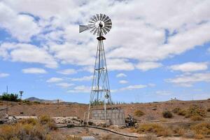 a windmill in the desert with a blue sky photo