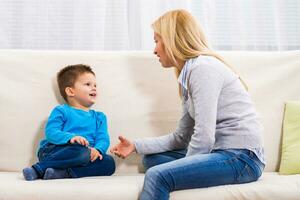 Mother and son sitting on sofa and talking about something. photo