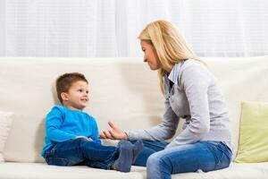 Mother and son sitting on sofa and talking about something. photo