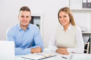 Businesswoman and businessman sitting in office and working together. photo