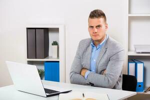 Angry businesswoman is sitting at his office. photo