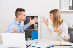 Businesswoman and businessman are very angry at each other and they are arguing at office. photo