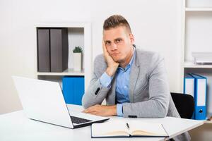 Depressed businessman sitting at his office . photo