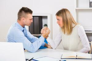 Arm wrestling between businessman and businesswoman at work. photo