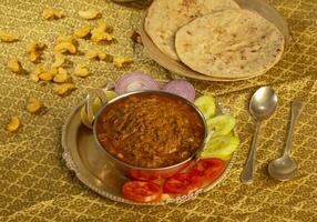 Rajasthani Famous Traditional Cuisine Haldi Sabji or Tukkar Served with Salad on White Background photo