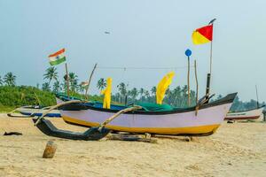 old fishing boats in sand on ocean in India on blue sky background photo