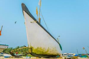 old fishing boats in sand on ocean in India on blue sky background photo