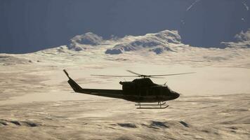 A helicopter flying over a snow covered mountain video