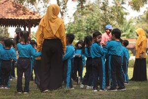 Magelang,Indonesia.12-05-2023.group of kindergarten school children and teachers playing and learning outdoors. photo