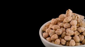 Chickpeas vegetables gyrating on a bowl in black background justified at right video