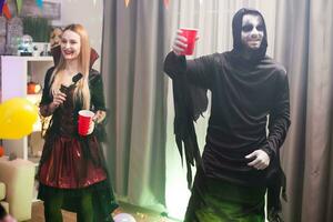Man dressed up like a spooky grim reaper at a halloween celebration with his friends. photo