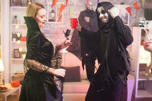 Grim reaper and beautiful vampire woman having fun at halloween party. photo