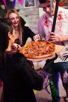 emocionado grupo de amigos acerca de Pizza a Víspera de Todos los Santos fiesta. foto