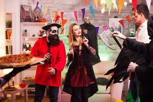 Young woman dressed up like a witch for halloween arriving with pizza at the party. photo