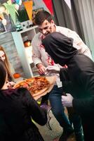 Rear view of people wearing halloween costumes excited about delicious pizza. photo