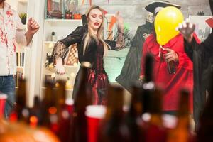 Beautiful young woman dressed up like a vampire showing dancing moves at halloween celebration with her friends. photo