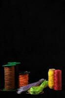 spools of thread and colored thread on a black background photo