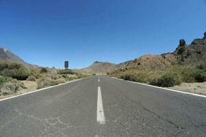 an empty road in the middle of a desert photo