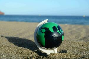 a painted egg on the beach with a green and black world map photo