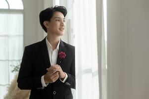 Portrait of young handsome groom in suit, preparing for wedding ceremony photo