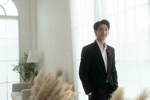 Portrait of young handsome groom in suit, preparing for wedding ceremony photo