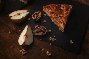 piece of pear pie on a black serving board on a wooden table photo