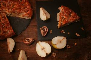 pear pie on a black serving board on a wooden table, photo