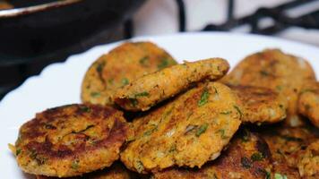 Fried carrot balls are smoking in a dish and cooking in a frying pan video