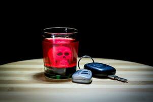 Drinking and driving concept. Car key on a wooden table and glass of alcohol, black background. photo
