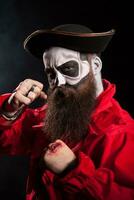 Medieval bearded man with pirate costume for halloween over black background. photo