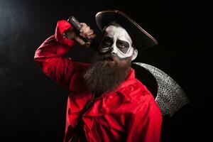 Crazy man dressed up like a medieval pirate with long beard and his axe for halloween over black background. photo