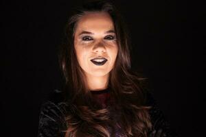 Attractive woman in a witch outfit for halloween looking at the camera over black background. photo