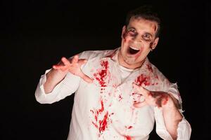 persona poseído por un zombi cubierto en sangre terminado negro antecedentes. Víspera de Todos los Santos traje. foto