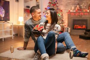 Loving couple with magic gift box celebrating christmas. Warm fireplace. photo